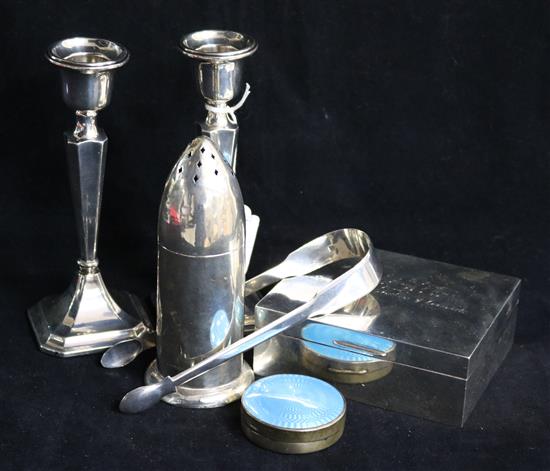 A pair of silver candlesticks, bullet shaped sifter and three other items.